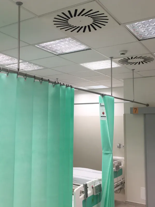 Instalovaný systém stropních zástěn s držáky procházejícími stropním podhledem a se skládanými závěsy